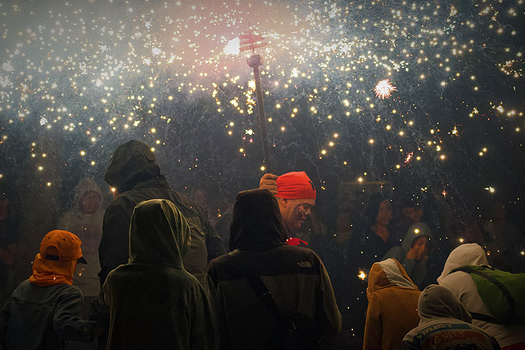 Participants en un correfoc envoltats d’espurnes durant una festa major.
