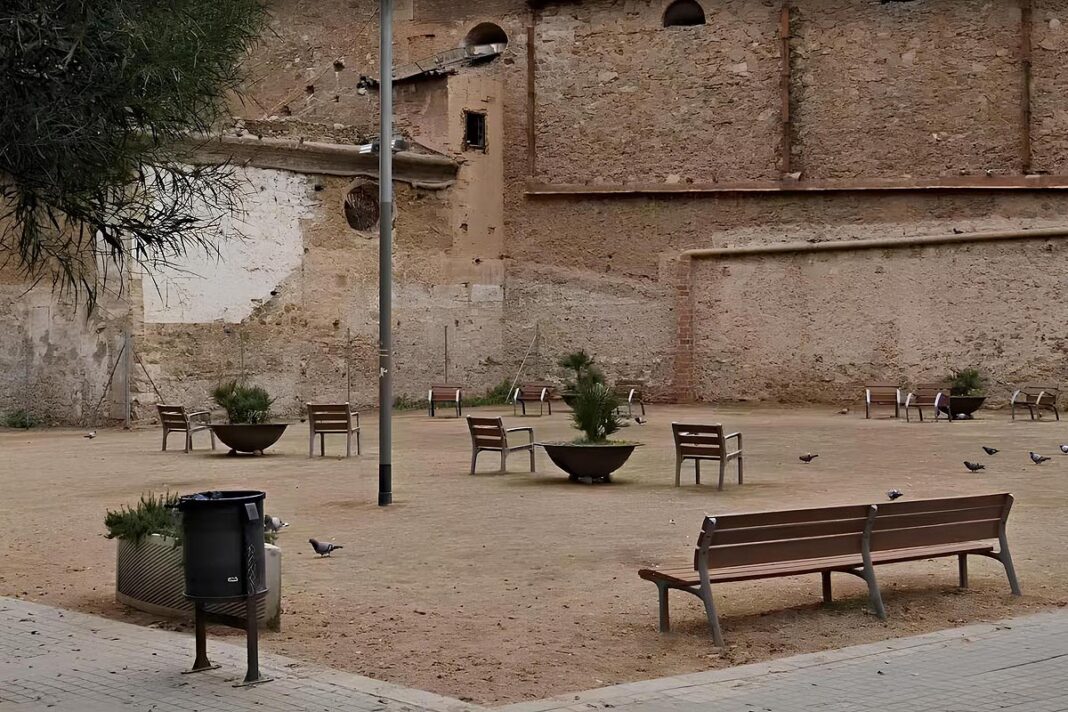 Jardins de les Dones de la Motor Ibèrica, amb bancs i la façana de la Capella dels Segadors al fons