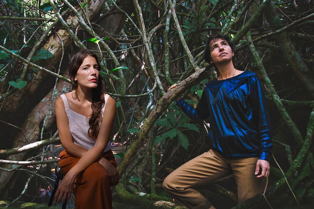 Dues artistes entre arbres i vegetació en una imatge del projecte 'Lo que se sabe invisible'.