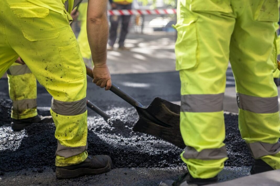Treballadors estenent asfalt sobre una calçada durant uns treballs de pavimentació