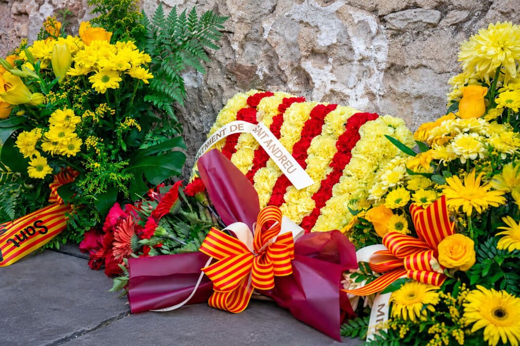 Corones i rams de flors amb llaços de la senyera en una ofrena floral.