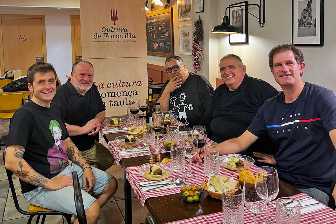 Cinc membres de la Junta Directiva de l'Associació Catalana de l'Esmorzar de Forquilla asseguts a una taula amb plats i vi al restaurant L'Andreuenc.