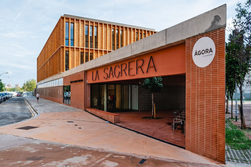 Façana principal i accés del CEM La Sagrera amb revestiment d'obra vista i estructura superior de lames de fusta al carrer de Bonaventura Gispert.